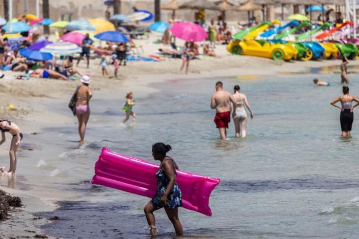 Touristen genießen das sonnige, warme Wetter am Strand von Peguera in Calvia, Mallorca. Foto: epa/Cati Cladera