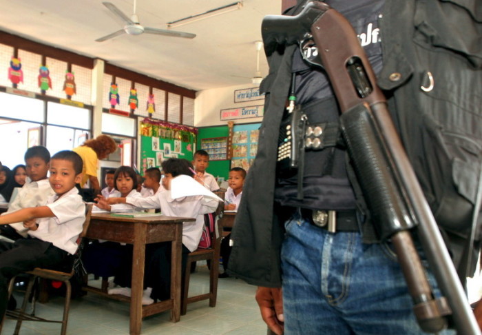 Ein Soldat bewacht den Unterricht von buddhistischen und muslimischen Schülerinnen und Schülern in Pattani. Foto: epa/Nakharin Chinnawornkomol