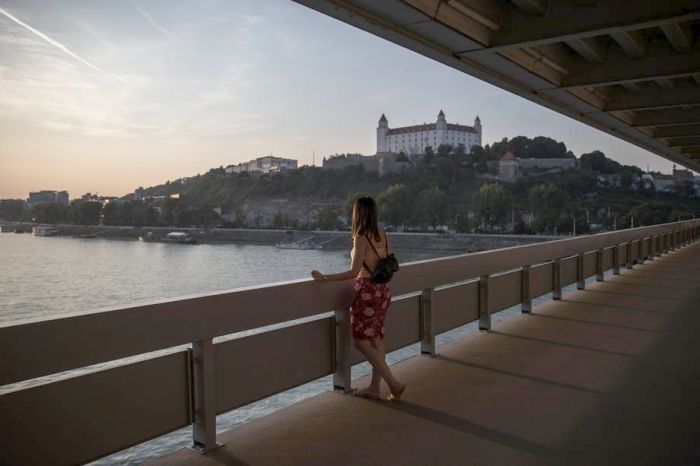 eine Frau schaut während des Sonnenuntergangs in Bratislava von einer Brücke aus. Foto: epa/Martin Divisek