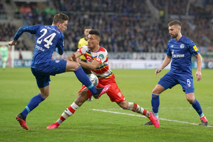 Der Mainzer Karim Onisiwo (M) und die Schalker Amine Harit (l) und Matija Nastasic kämpfen um den Ball. Foto: Thomas Frey/Dpa