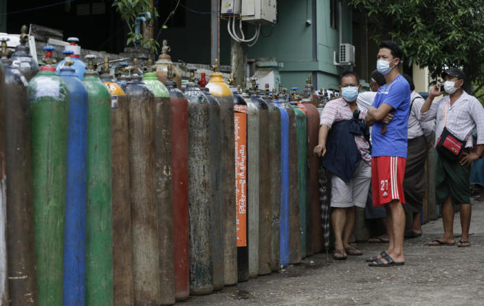 Menschen in Myanmar warten in der Nähe von Sauerstoffflaschen, die vor einer Sauerstofffabrik in Yangon zum Nachfüllen aufgereiht sind. Foto: epa/Lynn Bo Bo