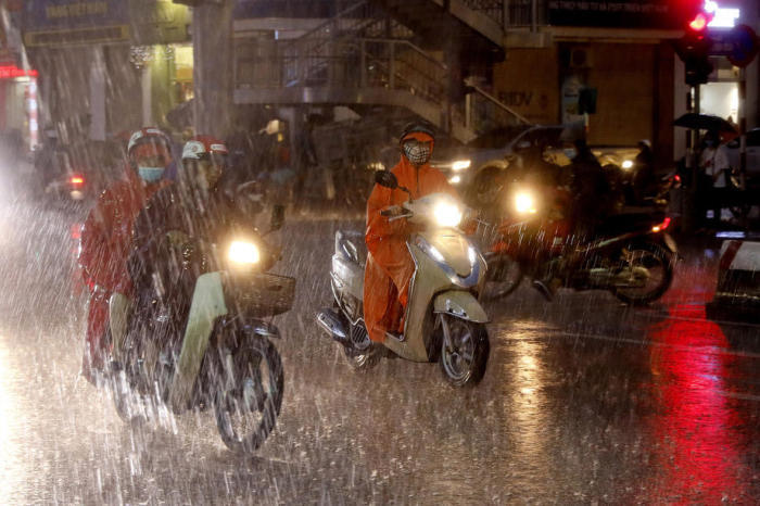 In Hanoi fahren Menschen bei starkem Regen, den der Tropensturm Podul mit sich gebracht hat, auf Motorrädern. Foto: epa/Minh Hoang