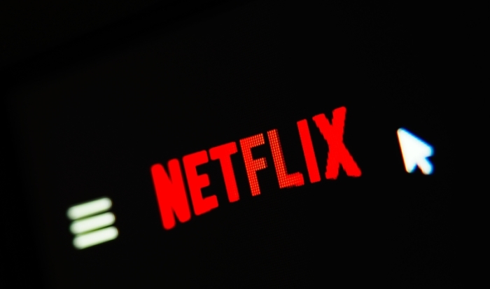 Ein Mauszeiger ist auf einem Computerbildschirm neben dem Logo des US-amerikanischen Online Filmportals «Netflix» zu sehen. Foto: Nicolas Armer/Dpa