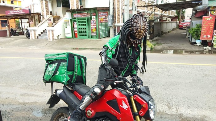 Grab-Fahrer Thoraphat, 41, verkleidet sich als Predator, um seinen Kunden ihre Bestellungen an die Haustür zu bringen und konnte mit dieser Idee seine Tageseinnahmen erhöhen. Foto: Sophon Cable Tv