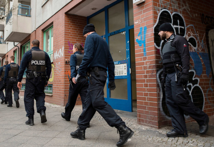 Polizeibeamte verlassen ein Wohnhaus im Berliner Bezirk Neukölln nach einer Razzia. Foto: epa/Gregor Fischer