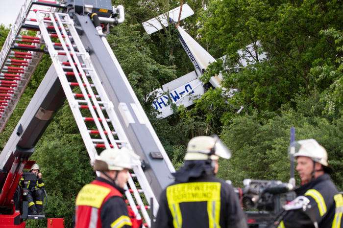 Ein Kleinflugzeug hängt neben einem Flugfeld in den Bäumen. Mitglieder der Feuerwehr Dortmund sind bei der Bergung im Einsatz. Foto: Marius Becker/Dpa
