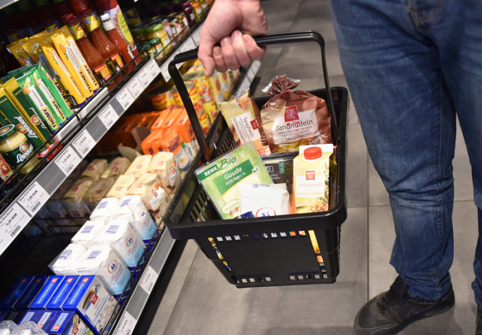 In einer Tankstelle steht ein Mann mit einem Einkaufskorb mit Lebensmitteln vor einem Regal. Foto: Caroline Seidel/Dpa