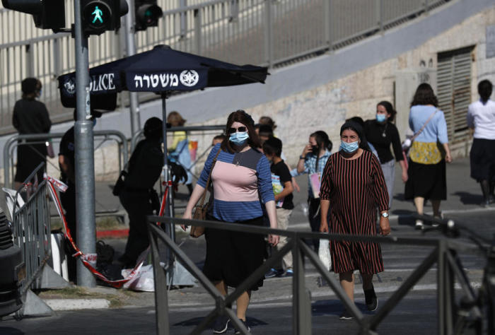 Tragende Schutzmasken passieren das blockierte ultra-orthodoxe Stadtviertel der Römer in Jerusalem. Foto: epa/Atef Safadi