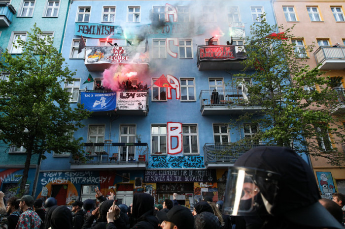 Demonstranten mit Bengalfackeln stehen auf Balkonen eines Gebäudes der linken Szene in der Rigaer Straße. Foto: epa/Omer Messinger