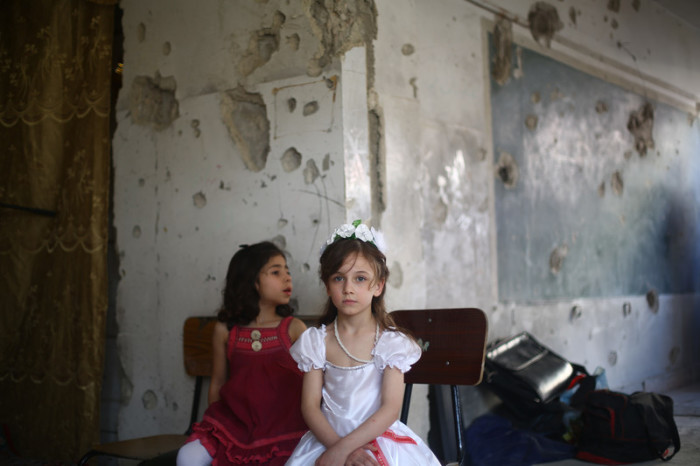 Zwei Mädchen sitzen in einer bei einem Bombenangriff zerstörten Schule in Duma, Syrien. Foto: epa/Mohammed Badra
