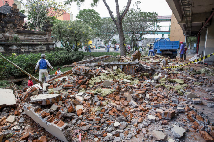 Arbeiter säubern Teile eines Einkaufszentrumgebäudes, das nach einem Erdbeben zusammenbrach. Foto: epa/Made Nagi