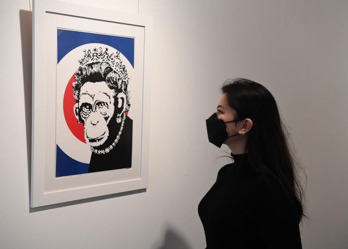 Ein Mitarbeiter der Galerie posiert neben einem Kunstwerk mit dem Titel 