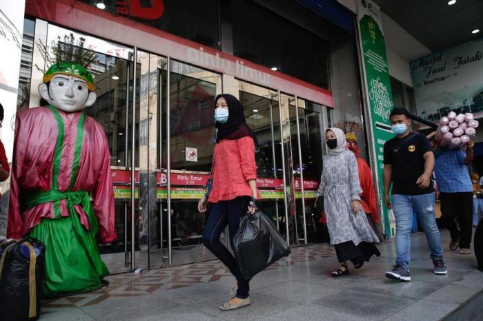 Besucher tragen Schutzmasken, wenn sie ihre Habseligkeiten tragen, gehen an einem Einkaufszentrum in Jakarta vorbei. Foto: epa/Adi Weda
