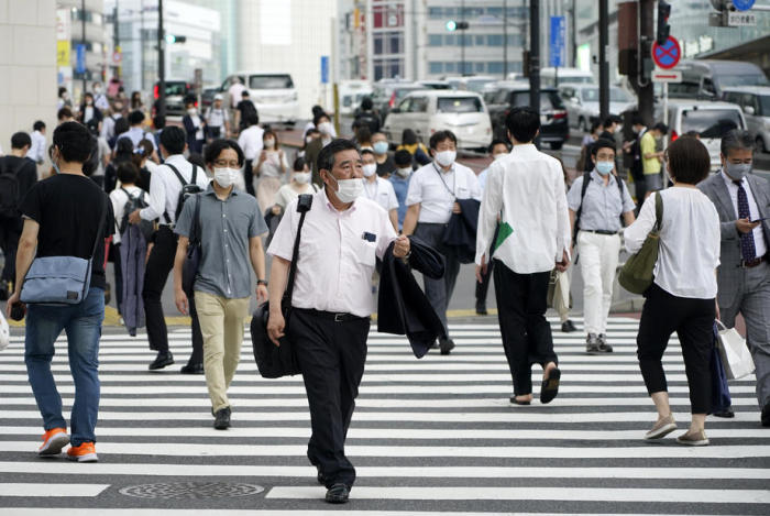 Fussgänger mit Schutzmasken gehen auf einer Strasse im Shinjuku-Distrikt in Tokio. Foto: epa/Franck Robichon