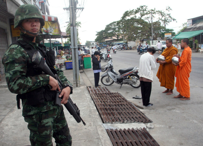 Ein thailändische Soldat sichert den morgenlichen Almosengang der Mönche in Pattani. Foto: epa/Abdullah Wangni