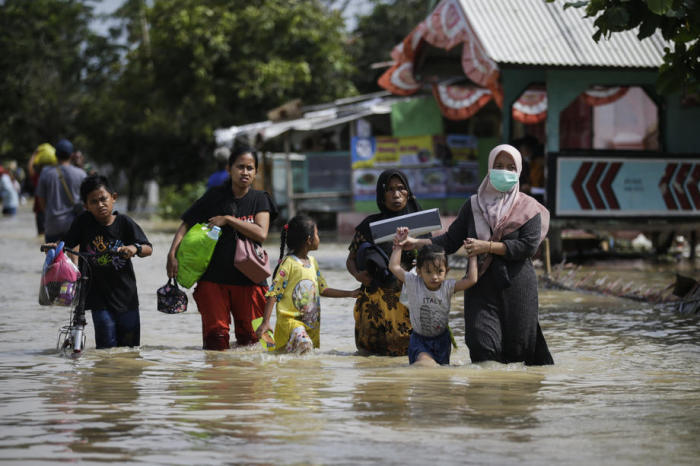 Die Leute tragen ihre Habseligkeiten, während sie durch das Hochwasser in Pebayuran, Bekasi, West Java waten. Foto: epa/Mast Irham