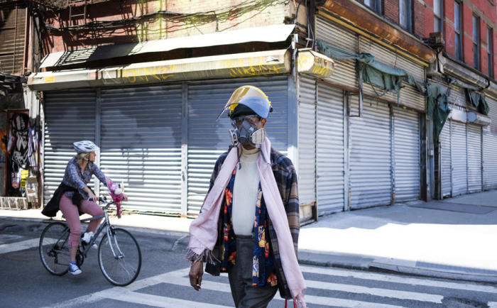 Ein Mann in Schutzausrüstung läuft an geschlossenen Geschäften in New York vorbei. Foto epa/JUSTIN LANE