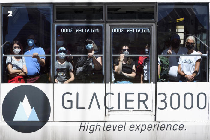 In Les Diablerets fahren Touristen mit Gesichtsschutzmasken mit der Seilbahn von Glacier 3000. Foto: epa/Laurent Gillieron