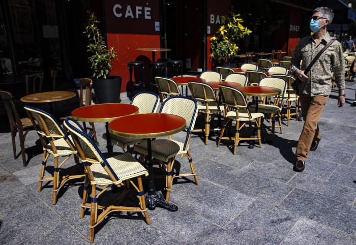 Ein Mann mit einer Gesichtsmaske geht in Paris an einem Café vorbei. Foto: epa/Ian Langsdon