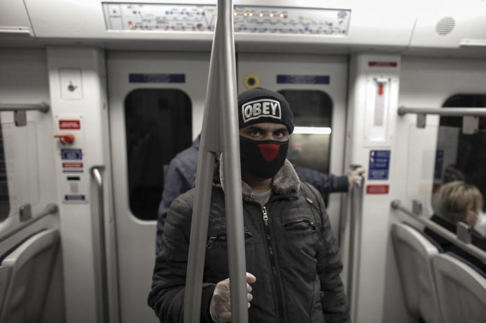 Ein mit einem Gesichtsschutz maskierter Mann fährt in einem U-Bahn-Wagen in Athen. Foto: epa/Kostas Tsironis