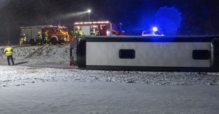 Ein Reisebus liegt umgestürzt neben der B10 in einem Feld. Bei schneeglatter Fahrbahn und starkem Wind kam der Bus von Straße ab. Acht Insassen wurden leicht verletzt. Foto: Stefan Puchner/Dpa