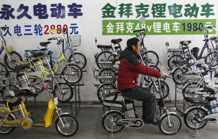 Ein Verkäufer eines Fahrradgeschäftes präsentiert Kunden ein Mini-E-Bike. Foto: epa/How Hwee Young