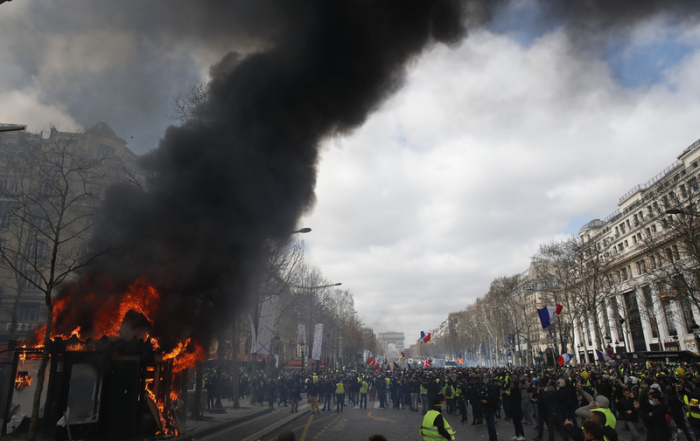 Ein Kiosk steht in Flammen bei «Gelbwesten»-Protesten auf dem Champs-Elysees. Dort und rund um den Triumphbogen an der Spitze der Prachtmeile kam es am Samstagvormittag zu Zusammenstößen zwischen Demonstranten und Polizei. Foto: Christophe Ena/Ap/dpa