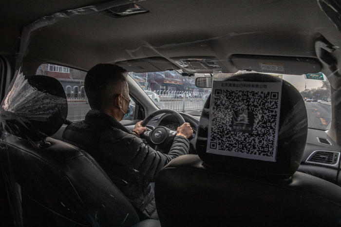 Ein DiDi-Taxi-Fahrer fährt ein Auto mit einem Plastikschild, das ihn von einem Fahrgast trennt, um die Ausbreitung der Coronavirus-Krankheit (Covid-19) zu verhindern, in Peking. Foto: epa/Roman Pilipey