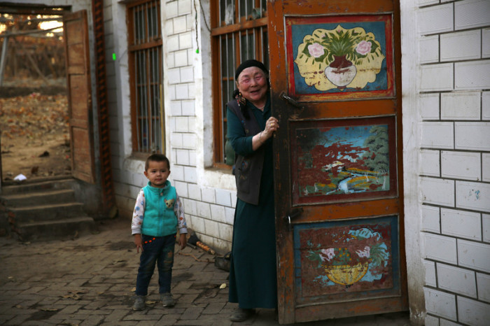 Eine ethnisch uigurische Frau und ein Kind begrüßen Besucher in ihrem Haus in Turpan in der Autonomen Provinz Xinjiang Uighur. Foto: epa/How Hwee Young