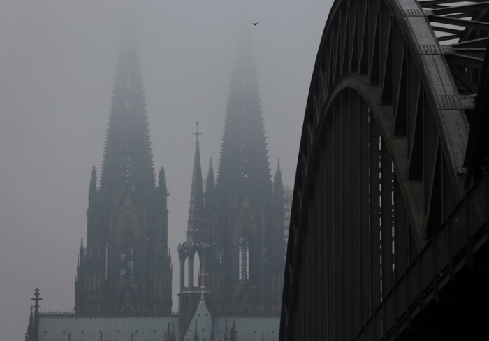 Die Spitzen des Domes verschwinden hinter der Hohenzollernbrücke im Nebel. Foto: Oliver Berg/Dpa