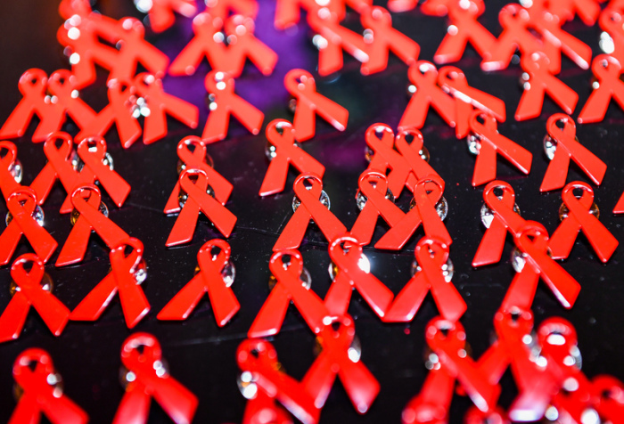 Aids-Schleifen liegen als Anstecknadeln auf einem Tisch. Foto: Jens Kalaene/Zb/dpa