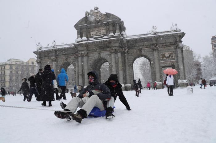 Menschen genießen den Schnee an der Puerta de Alcala in Madrid. Foto: epa/Ballesteros