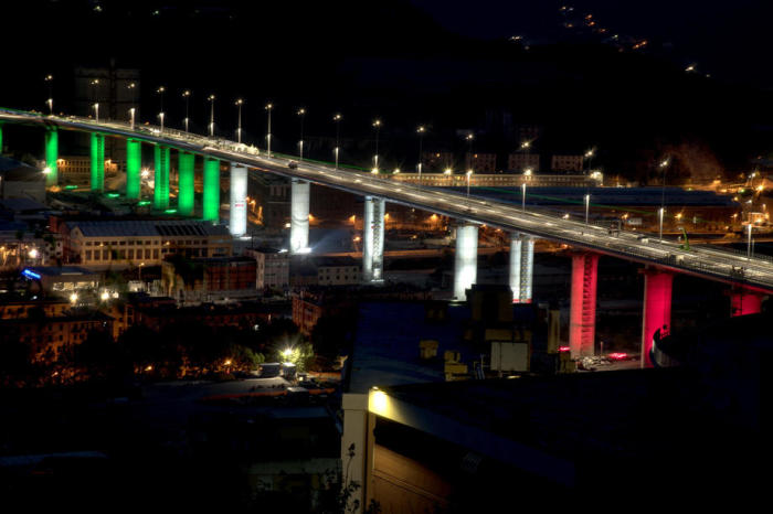 Eine Gesamtansicht zeigt die achtzehn Pfeiler der neuen Brücke von Genua, die am Vorabend der Installation des letzten Teils des Gerüsts in Genua mit den Farben der italienischen Flagge beleuchtet werden. Foto: epa/Luca Zennaro