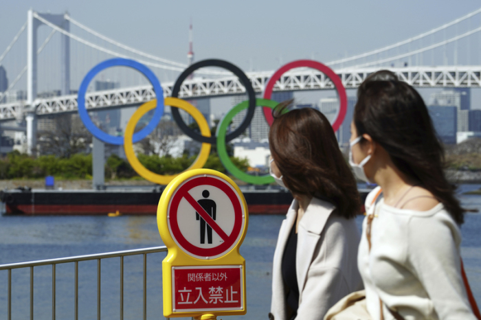 Zwei Frauen gehen an einem «Betreten verboten»-Schild vorbei. Dahinter sind die Olympischen Ringe zu sehen. Bei den Sommerspielen in Tokio dürfen wegen der Corona-Pandemie keine ausländischen Fans nach Japan einreisen.