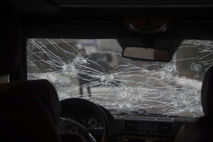 Das Glas der Windschutzscheibe eines Polizeiautos auf einer Straße ist zerbrochen und mit Einschusslöchern versehen. Foto: Vladimir Tretyakov