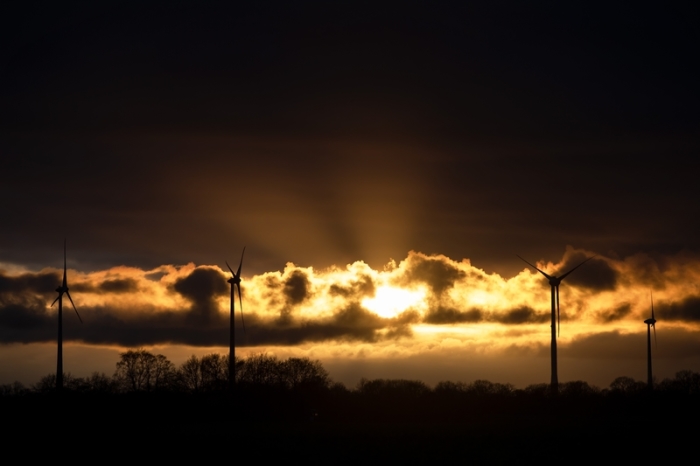 Windkraftanlagen zeichnen sich vor dem Sonnenuntergang ab. Foto: Sina Schuldt/Dpa