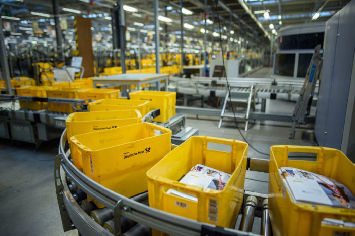 Gelbe Kisten zum Sortieren von Briefen laufen im Briefzentrum Kiel der Deutschen Post über ein Förderband. Foto: Gregor Fischer/Dpa