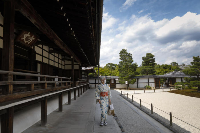 Eine Kimono bekleidete Frau mit einer Gesichtsmaske besucht den Tenryuji-Tempel in Kyoto. Foto: epa/Dai Kurokawa