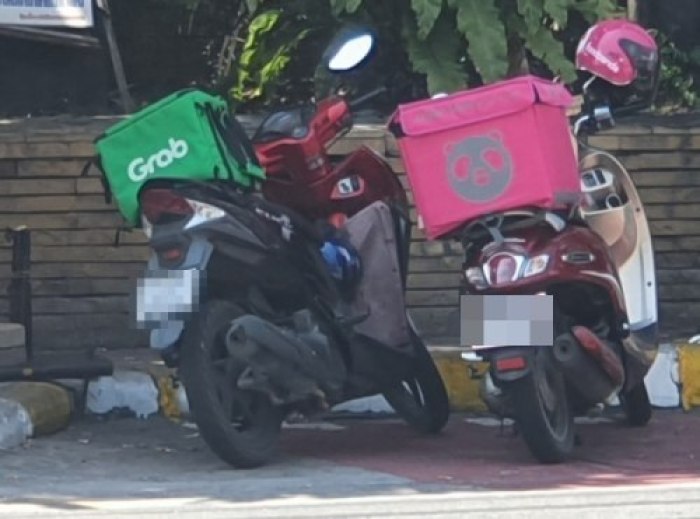 Abgestellte Motorräder von Boten der beiden Speiselieferdienst-Rivalen Grab (l.) und Foodpanda (r.) vor der Royal Garden Plaza in Pattaya. Foto: Jahner