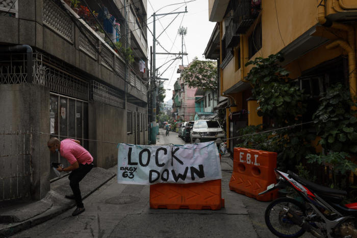 Ein Regierungsmitarbeiter durchquert die Beschilderung in einem abgesperrten Dorf in Manila. Foto: epa/Mark R. Cristino
