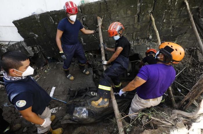 Katastrophenhelfer bergen die Leiche eines Taifun-Opfers, das starb, nachdem es unter einer eingestürzten Mauer eingeklemmt worden war, die durch eine Überschwemmung in der Stadt Marikina entstanden war. Foto: epa/Rolex Dela Pena