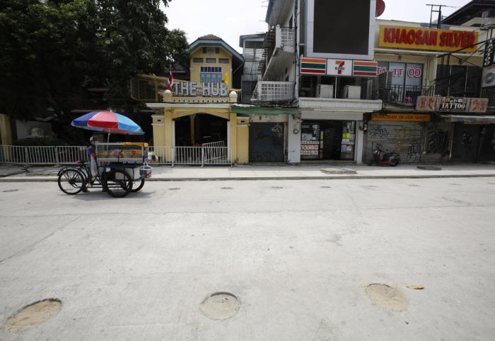 Ein Straßenhändler schiebt seinen mobilen Verkaufsstand durch die verwaiste Khao San Road in Bangkok. Außerhalb von Coronazeiten geht in der Touristenmeile die Post ab. Foto: epa/Narong Sangnak