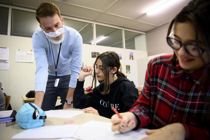 Lehrer Matthieu Macchi trägt während des Unterrichts eine transparente Schutzmaske, um einem seiner Schüler zu helfen. Foto: epa/Laurent Gillieron