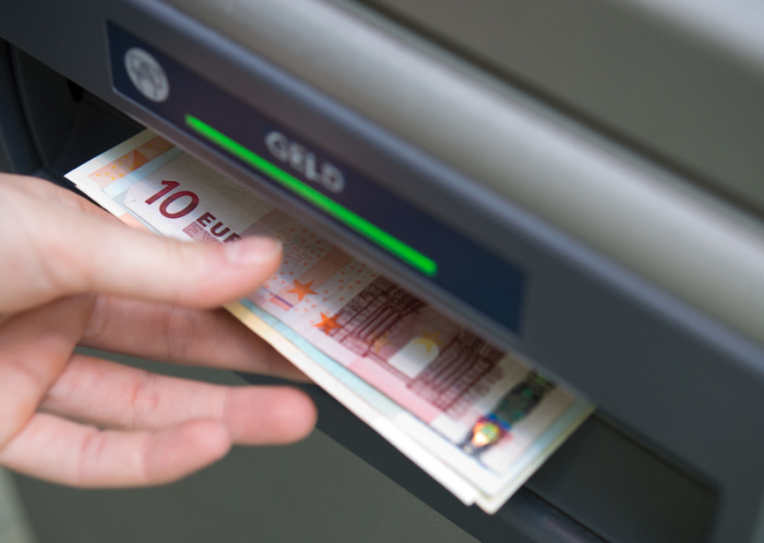Eine Frau zieht Geldscheine aus einem Geldautomaten. Foto: Andrea Warnecke/dpa-tmn/dpa
