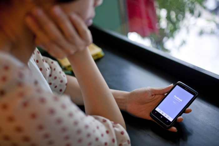 Eine junge Frau benutzt in einem Café in Hanoi die soziale Netzwerkseite Facebook auf ihrem Telefon. Foto: epa/Luong Thai Linh