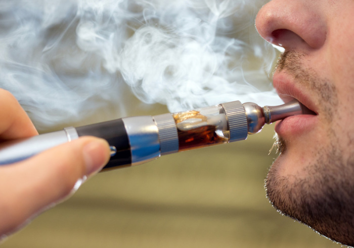 Ein Mann raucht eine elektrische Zigarette (E-Zigarette). Foto: Friso Gentsch/Dpa