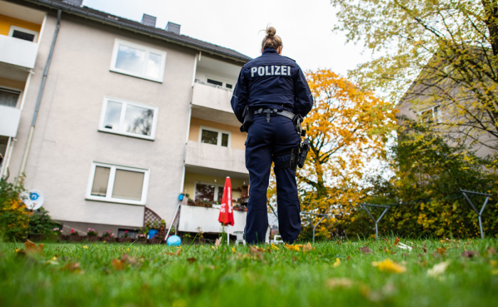 Eine Polizistin steht im Garten des Mehrfamilienhauses, wo gestern Abend eine 15-Jährige ihren dreijährigen Halbbruder in Detmold mit einem Messer getötet haben soll. Foto: Guido Kirchner/dpa