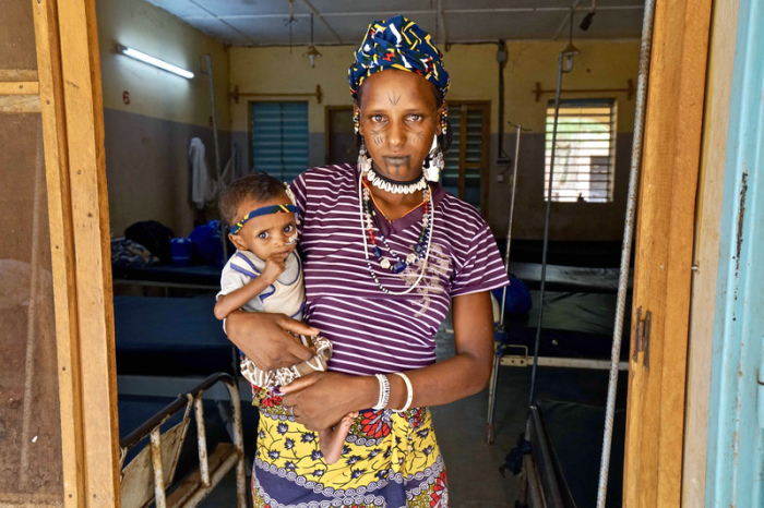 Eine Frau steht mit ihrem schwer unterernährten Kleinkind auf dem Arm in der Tür des Krankenhauses in einer von den Vereinten Nationen unterstützten Siedlung für Binnenflüchtlinge im Norden des Landes. Foto: Giles Clarke/dpa