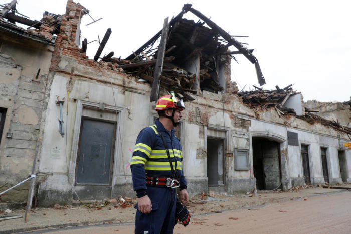 Ein Feuerwehrmann geht an einem durch ein Erdbeben beschädigten Gebäude in Petrinja, Kroatien, vorbei. Foto: epa/Antonio Bat