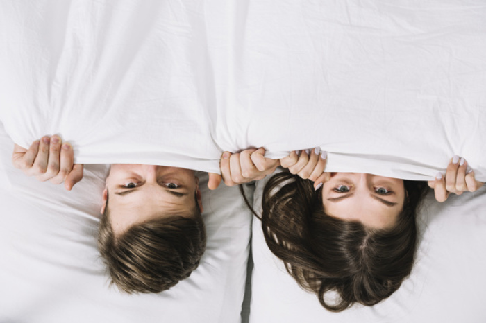 Ein junges Paar liegt im Bett. Foto: Freepik